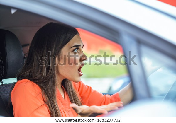 Stressed woman driver sitting\
inside her car. Angry female driver driving a car. Angry young\
woman stuck in a traffic jam. Woman annoyed in car. Girl stuck in\
traffic.