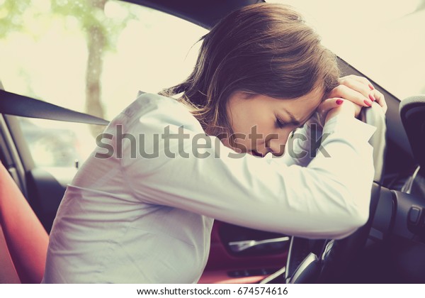 Stressed woman\
driver sitting inside her car\
