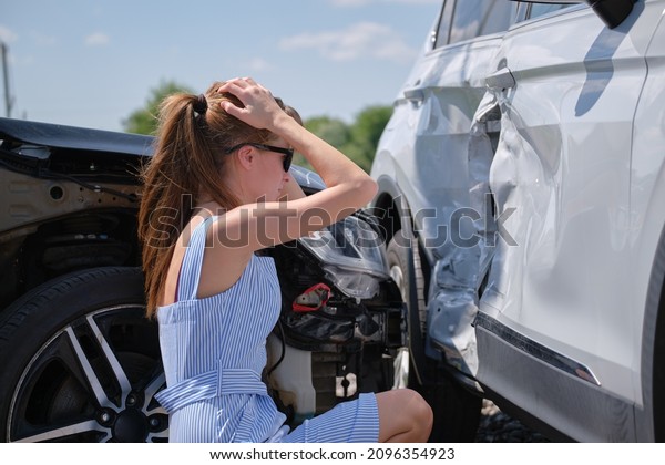 Stressed woman driver\
sitting on street side shocked after car accident. Road safety and\
insurance concept