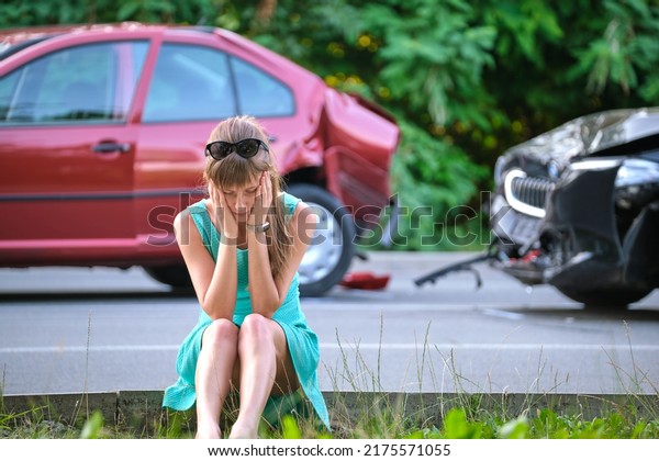 Stressed woman driver\
sitting on street side shocked after car accident. Road safety and\
insurance concept.