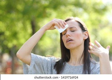 Stressed Woman Drying Sweat Using A Wipe In A Warm Summer Day In A Park