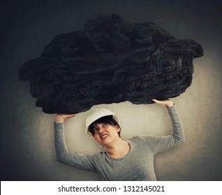 Stressed woman engineer holding a huge heavy stone above head. Metaphor for the individual's persistent struggle against the challenges of life. Making effort to carry a big rock, concept of burden.
