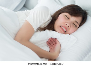 stressed woman with grinding teeth, bruxism symptoms; portrait of stressful, exhausted, tired sleeping woman grinding her teeth with stress; oral, dental care medical concept; asian adult woman model