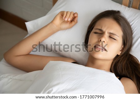 stressed woman with grinding teeth, bruxism symptoms; portrait of stressful, exhausted, tired sleeping woman grinding teeth with stress; oral, dental care medical concept; caucasian adult woman model
