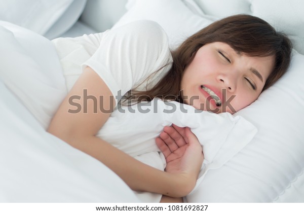 stressed woman with grinding teeth, bruxism\
symptoms; portrait of stressful, exhausted, tired sleeping woman\
grinding her teeth with stress; oral, dental care medical concept;\
asian adult woman\
model