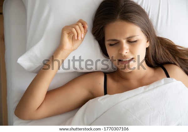 stressed woman with grinding teeth, bruxism\
symptoms; portrait of stressful, exhausted, tired sleeping woman\
grinding teeth with stress; oral, dental care medical concept;\
caucasian adult woman\
model