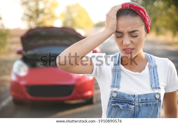 Stressed\
woman having headache near broken car\
outdoors