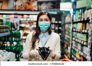 Stressed woman with mask shopping in grocery store with an empty wallet.Bankruptcy/recession.Covid-19 quarantine lockdown impact.Unemployed person in money crisis.Financial hardship.No income anxiety