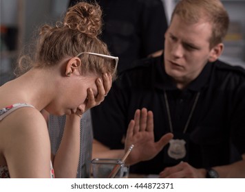 Stressed Woman At The Police Station Holding Head Down, Police Officer Trying To Calm Her Down