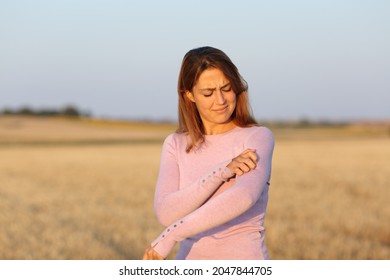 Stressed Woman Scratching Itchy Arm In A Harvested Field