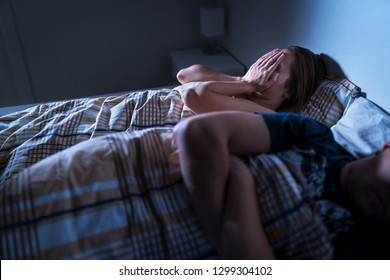 Stressed woman suffering in bad relationship. Ashamed man with guilt. Infidelity, jealousy, trust issues and mistrust concept. Couple with problems. Wife sulking at night in bed. Marriage in crisis.