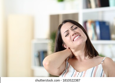 Stressed woman suffering neck ache in the living room at home