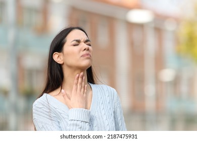 Stressed woman suffering sore throat standing in the street