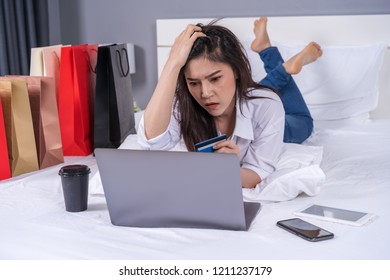 stressed woman using laptop for online shopping on a bed, and having problem with blocked credit card