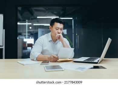 Stressed Young Asian Businessman Working From Office Report Annoyed With Low Sales. Nervous Boss See C Mistake Incorrect Information In Paper Document