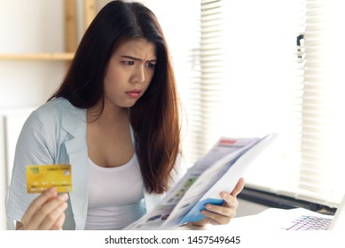 Stressed Young Asian Woman Hands Holding Dummy Credit Cards And Bills Feeling Shock And Trying To Find Money To Pay Credit Card Debt And All Loan Bills Put On Table. Financial Problem Concept.