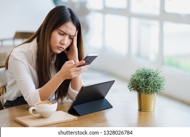 Stressed young asian woman having problem with not working smartphone or tablet in coffee shop cafe, Unhappy worried freelance working woman concept