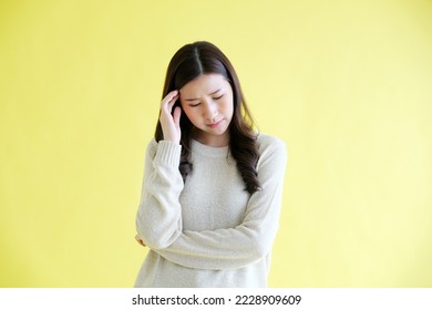 Stressed young asian woman standing over isolated yellow background - Shutterstock ID 2228909609