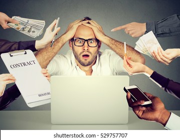 Stressed Young Business Man Sitting At Table In Office Working On Computer Overwhelmed By Errands Should Be Done. Busy Day Of An Employee Concept 