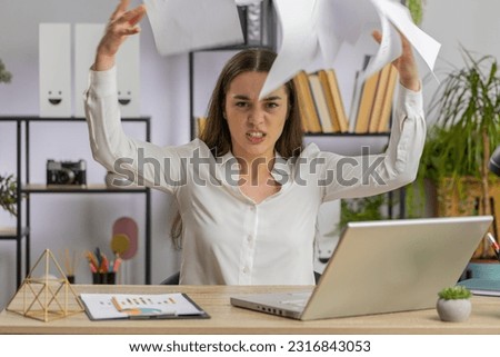 Stressed young business woman working looking at unpaid bank debt bills, doing paperwork, planning budget, calculate finances mortgage payments at office. Displeased freelancer girl throws paper bills