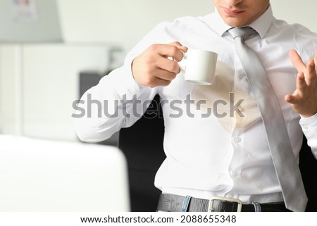 Stressed young businessman with coffee stains on his shirt in office