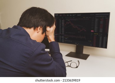 Stressed Young Businessman, Trader Or Investor Touch Head, Disappointed When Bad Investment Or Economic Crisis, Losing Money From Investing, Trading Stock, Cryptocurrency As Bitcoin On Laptop At Home.