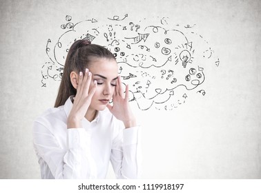 Stressed young businesswoman with long hair in a ponytail wearing a white shirt. She is having a headache and standing with closed eyes. An arrow sketch on a concrete wall.