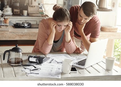 Stressed Young Caucasian Couple Facing Financial Problems, Not Able To Pay Off Their Loan Because Of Many Debts. Woman With Headache And Worried Man Feeling Stress, Reading Notification From Bank