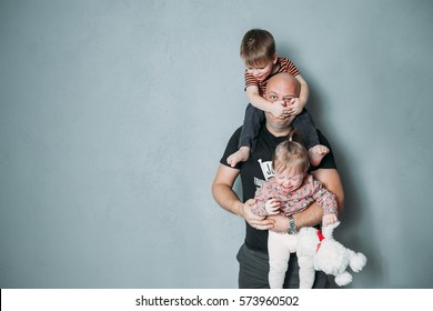 stressed young dad with two small children in his arms - Shutterstock ID 573960502