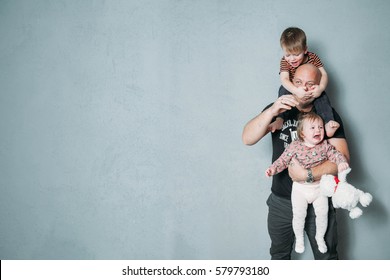 Stressed Young Dad With Two Small Children In His Arms