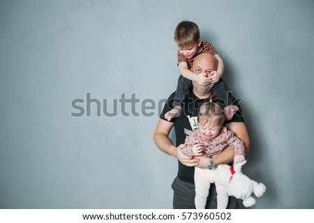stressed young dad with two small children in his arms
