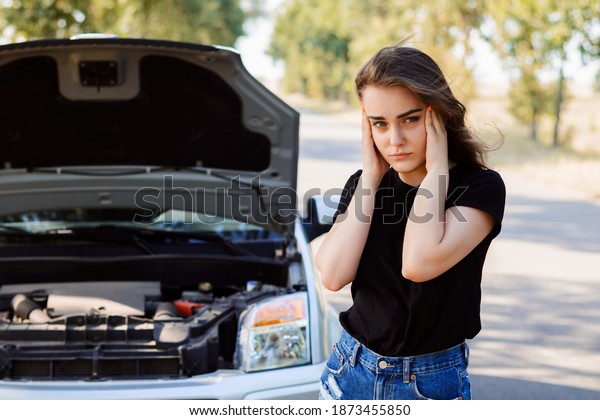 Stressed young driver girl with a\
broken down car in the middle of nowhere waiting for a\
help
