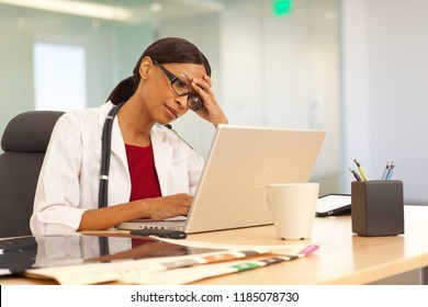 Stressed Young Female Physician Using Laptop Computer At Work