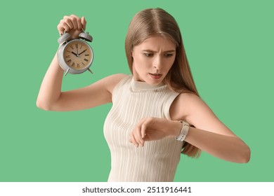 Stressed young woman with alarm clock looking at wristwatch on green background. Deadline concept - Powered by Shutterstock