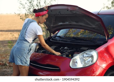 Stressed Young Woman Fixing Broken Car Outdoors