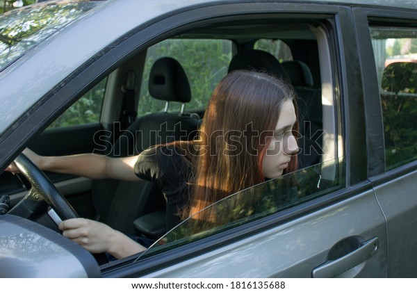 The stressed young woman\
with red hair is driver student. She is very worried and afraid to\
drive.