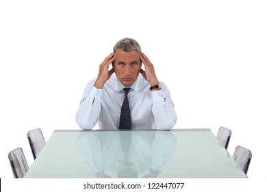 Stresses Senior Businessman Sat In Empty Boardroom