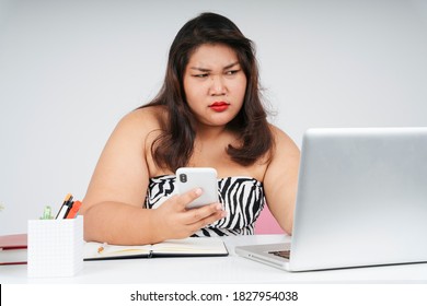 Stressful Asian Chubby Woman Working On Laptop And Smartphone With Serious Looking.