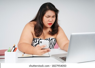 Stressful Asian Chubby Woman Working On Laptop And Smartphone With Serious Looking.