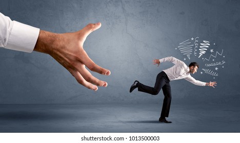 Stressful businessman running from a big hand concept on background