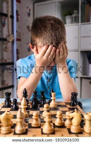 stressful child at the chessboard. boy was upset about losing a game of chess