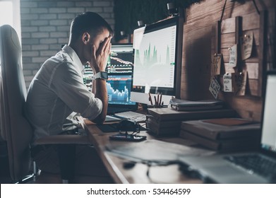 Stressful day at the office. Young businessman holding hands on his face while sitting at the desk in creative office  - Shutterstock ID 534464599
