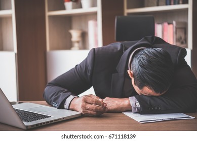 Stressful male sleeping on the table with laptop and documents, shot in the office room - Shutterstock ID 671118139