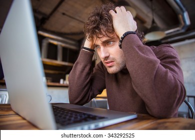 Stressful upset desperate handsome curly man in brown sweetshirt working using laptop and having headache - Powered by Shutterstock