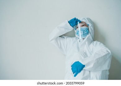 Stressful - Worried Asian Medication Staff Sitting On A Chair Against The Wall, Healthcare Worker Hard Working In Hospital. Overworked Health Care Worker - Nurse Feels Tired.