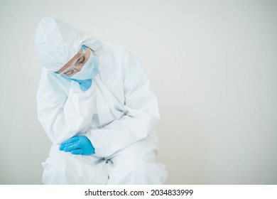 Stressful - Worried Asian Medication Staff Sitting On A Chair Against The Wall, Healthcare Worker Hard Working In Hospital. Overworked Health Care Worker - Nurse Feels Tired.