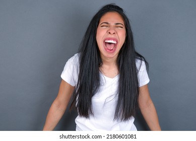 Stressful Young Hispanic  Woman Wearing White T-shirt Over Grey Background Screams In Panic, Closes Eyes In Terror, Keeps Hands On Head, Finds Out Terrified News, Can't Believe It.