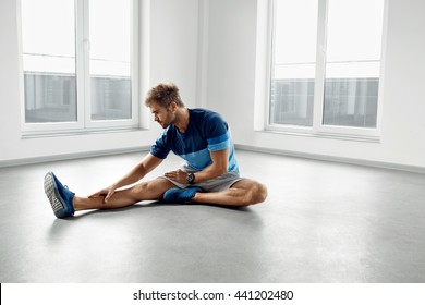 Stretch Body Exercise. Handsome Man Stretching Before Workout. Healthy Muscular Athletic Active Fitness Male Model In Fashion Sportswear Doing Stretches, Warming Up, Exercising Indoors. Sports Concept