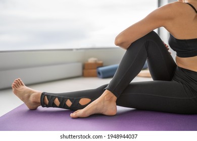 Stretch exercise at home fit Yoga woman stretching lower back for spine health relaxing at home. Seated twist with leg extended marichyasana.