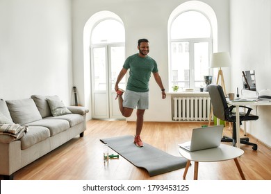 Stretch. Full Length Shot Of Male Fitness Instructor Stretching, Showing Exercises While Streaming, Broadcasting Video Lesson On Training At Home Using Laptop. Sport Online Concept. Horizontal Shot